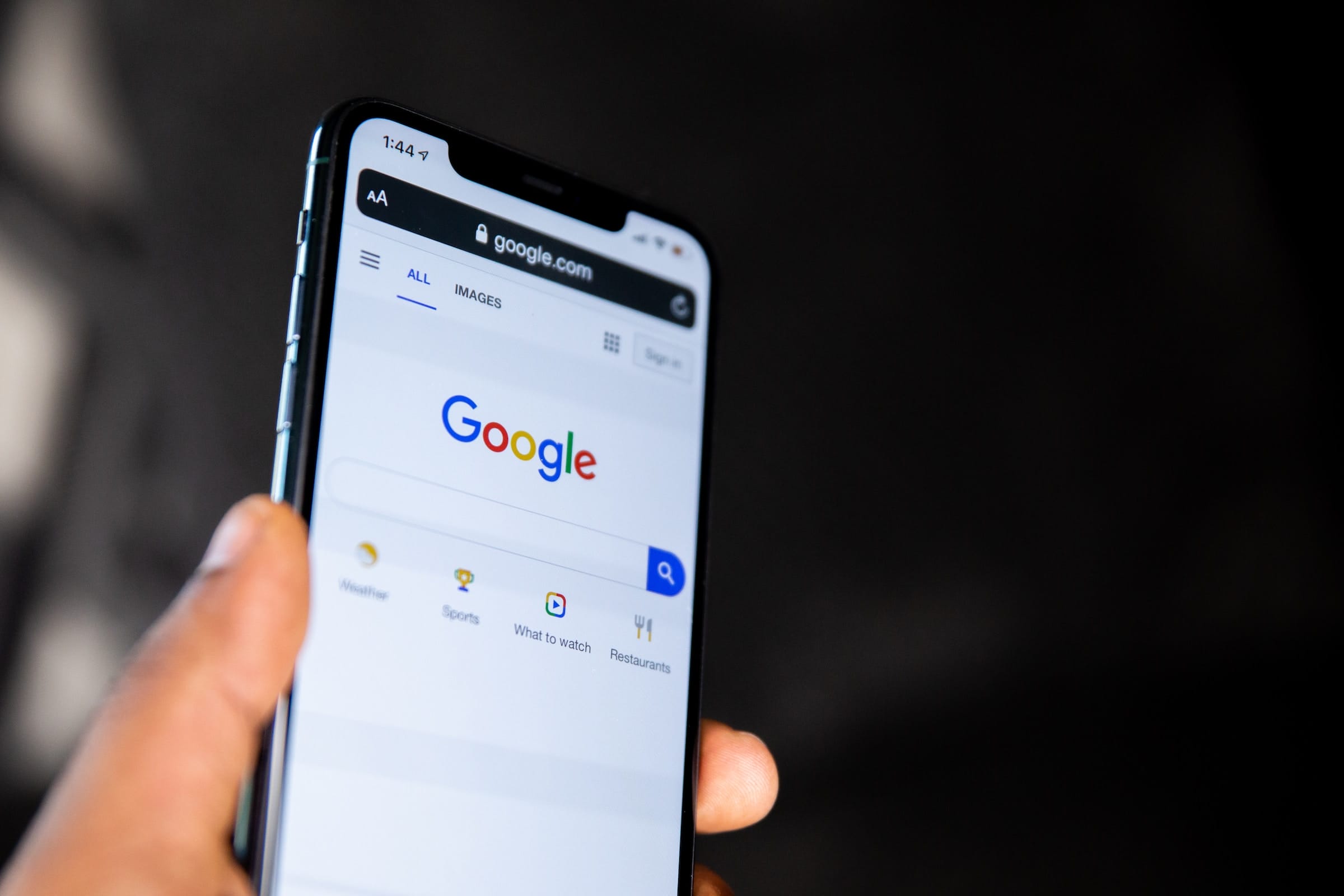 Рука держит смартфон с открытым поиском Google