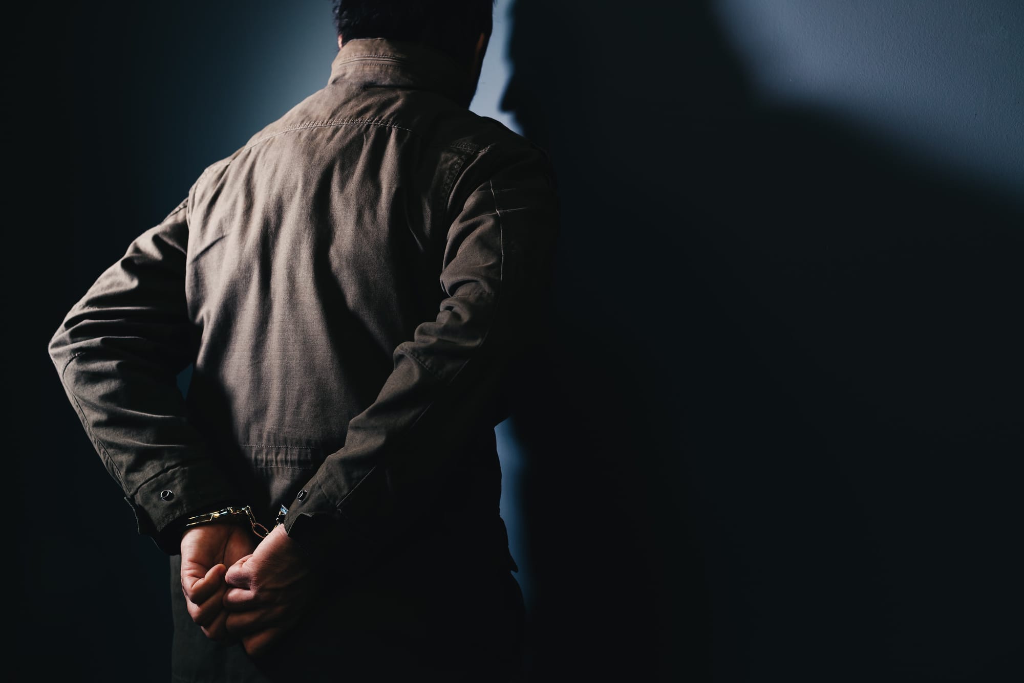 Человек в наручниках стоит у стены