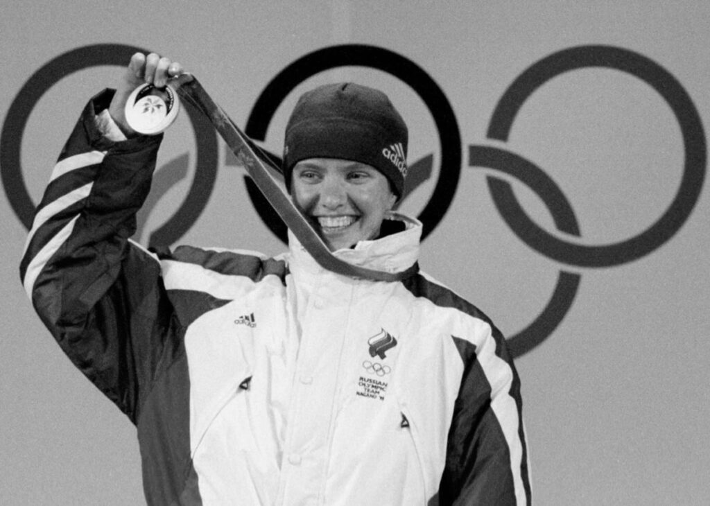 Galina Koukleva of Russia shows her Olympics gold medal during the biathlon awarding ceremony in Nagano February 15. [Germany's Ursula Disl won the silver and her compatriot Katrin Apel took the bronze.]
